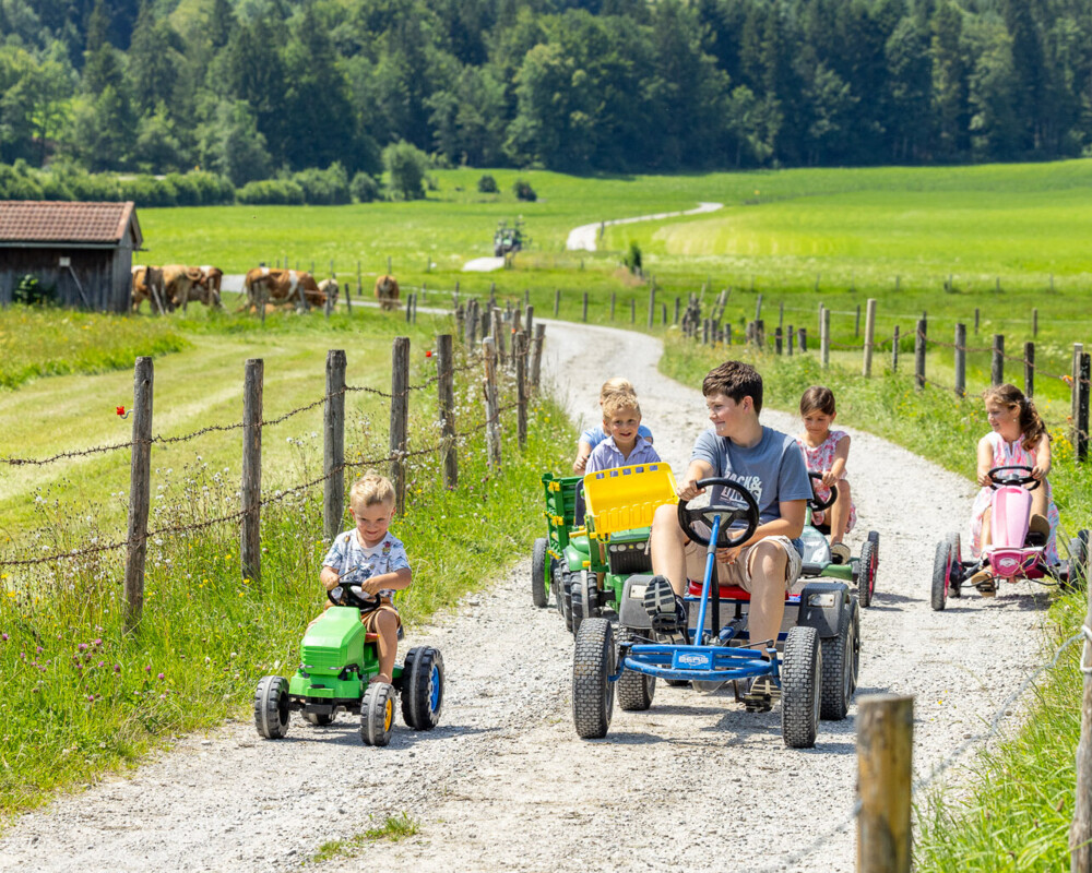 Kinder auf dem Feldweg mit Spielfahrzeugen