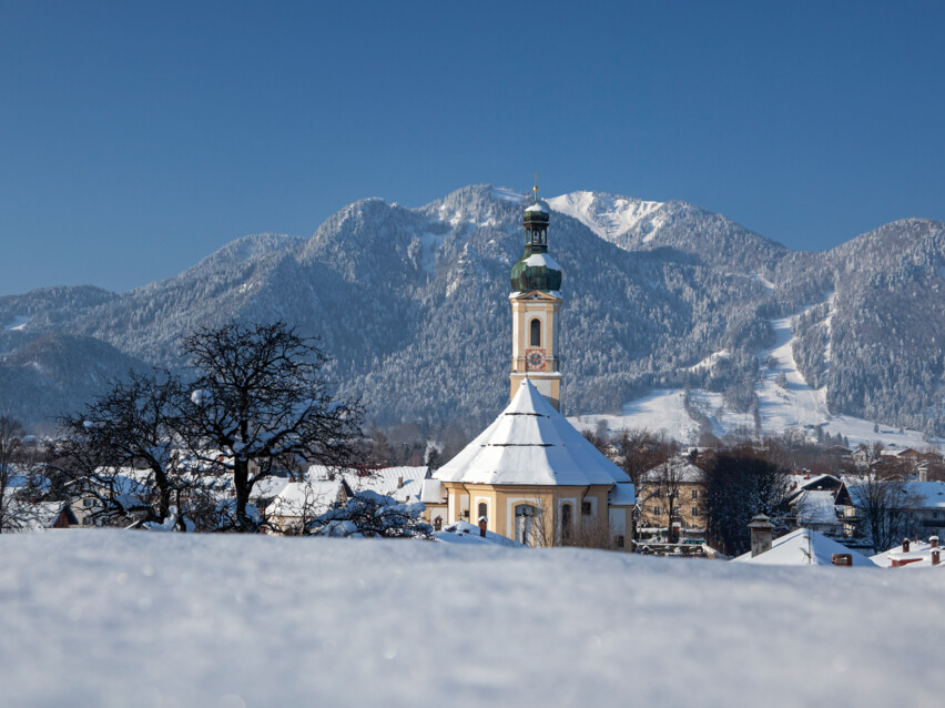 Ortsmitte Lenggries mit Pfarrkirche Sankt Jakob und Brauneck im Winter