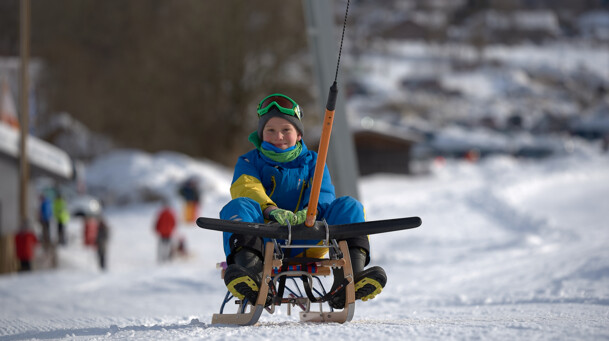 Junge mit Schlitten am Rodellift in Lenggries